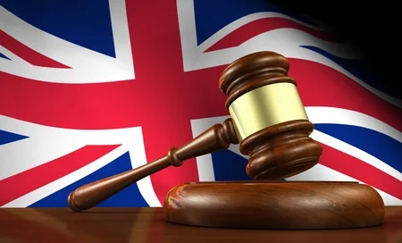 Gavel and block symbolizing law and justice in the UK against a British flag background.